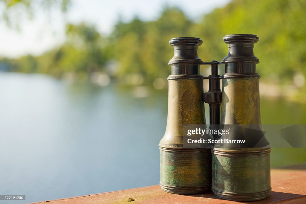 Old fashioned binoculars on a table beside a lake