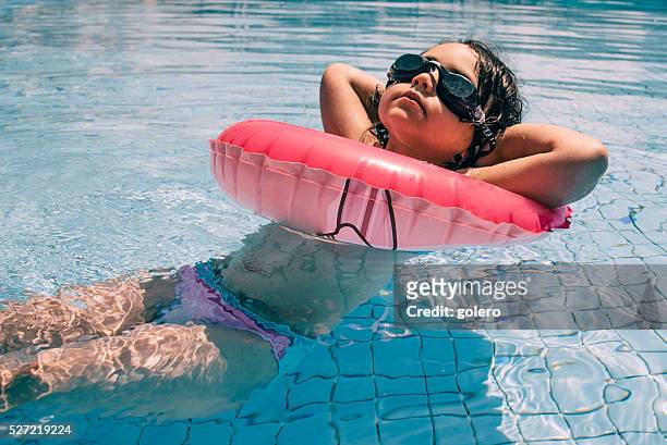 coole kleines mädchen im bikini und sonnenbrille im pool schwimmen - tube girl stock-fotos und bilder