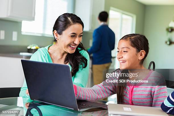 mother uses laptop as she homeschools daughter - texas family stock pictures, royalty-free photos & images