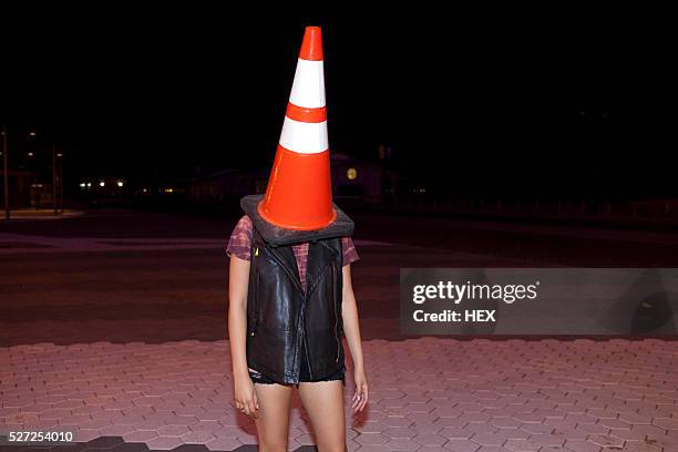 playful young woman with a traffic cone on her head - traffic cone 個照片及圖片檔