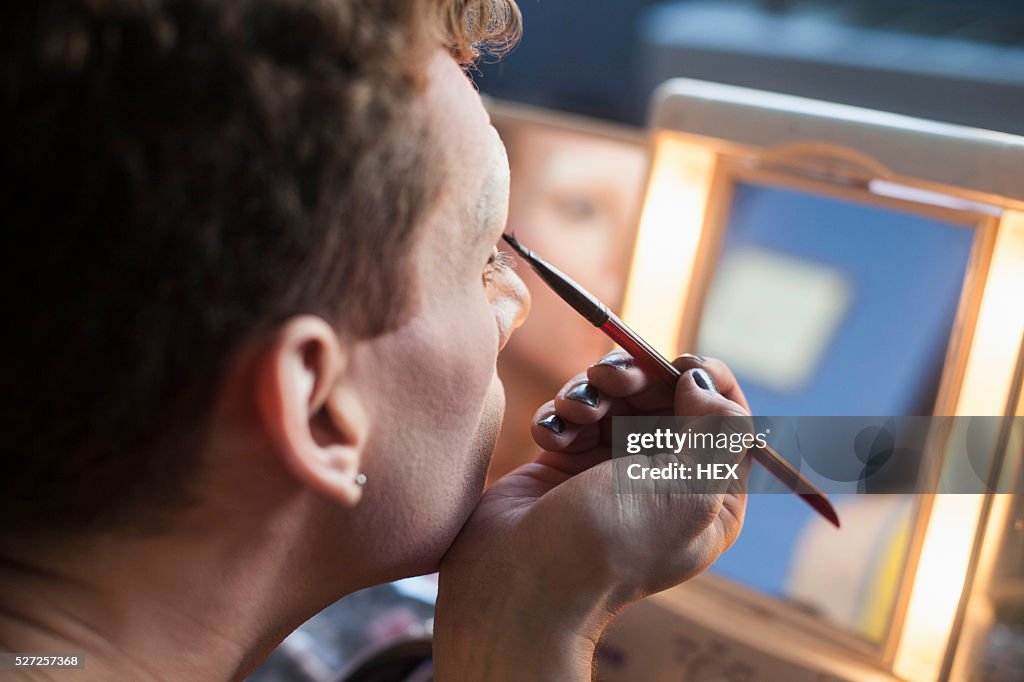 Young man applying drag makeup