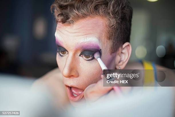 young man applying drag makeup - drag queen stockfoto's en -beelden