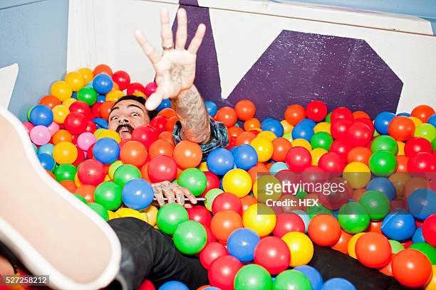 young man playing in a ball pit - adult ball pit stock pictures, royalty-free photos & images