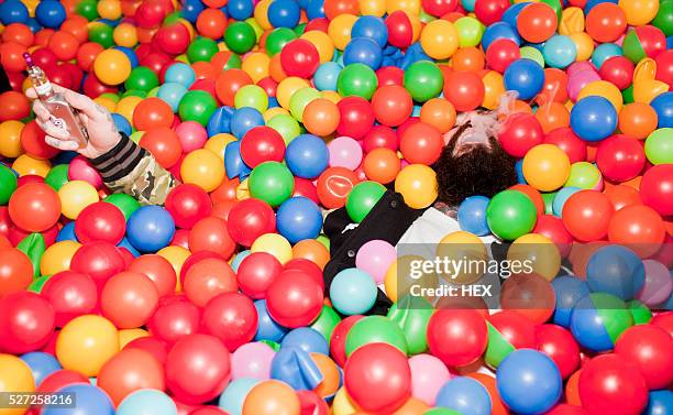 young man playing in a ball pit - adult ball pit stock pictures, royalty-free photos & images