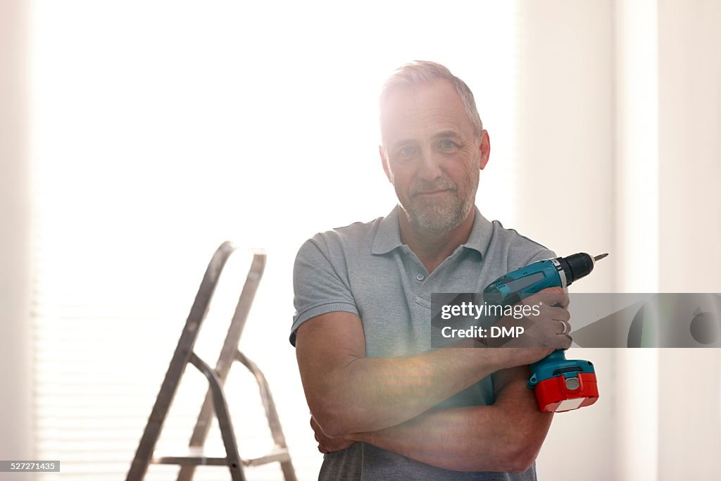 Mature man at home with a drill machine
