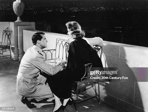 American model and actress Suzy Parker and British-born actor Cary Grant share an intimate moment in a scene from Stanley Donen's 'Kiss Them for Me,'...