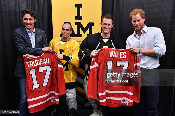 Prince Harry holds the Wales hockey jersey up with Canadian Prime Minister Justin Trudeau as they meet with Invictus Games athletes after a...