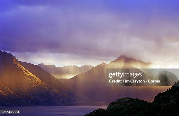 The late sun catches a rain shower on Lake Wakatipu, Queenstown, New Zealand. Queenstown is nestled on the shores of the crystal clear waters of Lake...