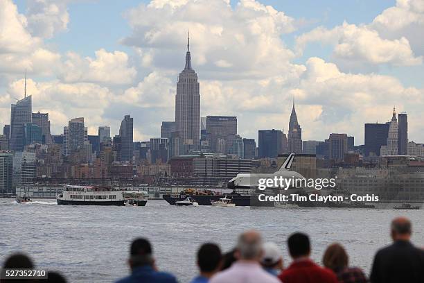 The Space Shuttle Enterprise passes lower Manhattan on a barge along the Hudson River as it completes her journey to the Intrepid Sea, Air and Space...