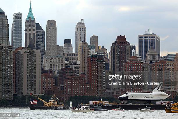 The Space Shuttle Enterprise passes lower Manhattan on a barge along the Hudson River as it completes her journey to the Intrepid Sea, Air and Space...
