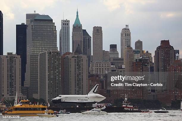 The Space Shuttle Enterprise passes lower Manhattan on a barge along the Hudson River as it completes her journey to the Intrepid Sea, Air and Space...