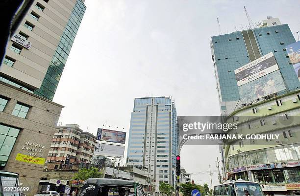 Bangladeshi commuters make their way past a high-rise building in downtown Dhaka, 25 April 2005. The recent collapse of a factory that killed 73...