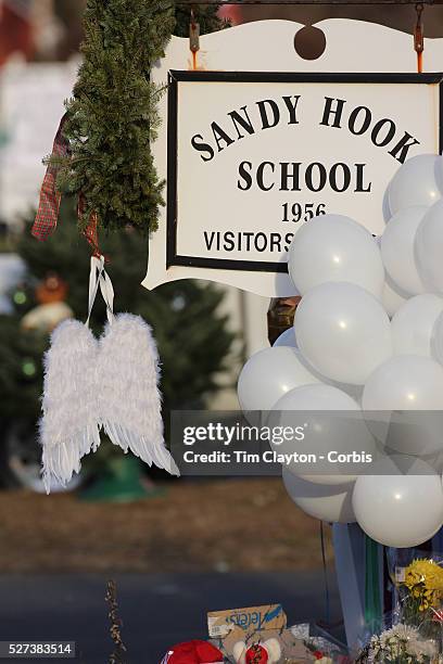 Angel wings hang from the school sign where a shrine created under the school sign in Sandy Hook after yesterday's shootings at Sandy Hook Elementary...