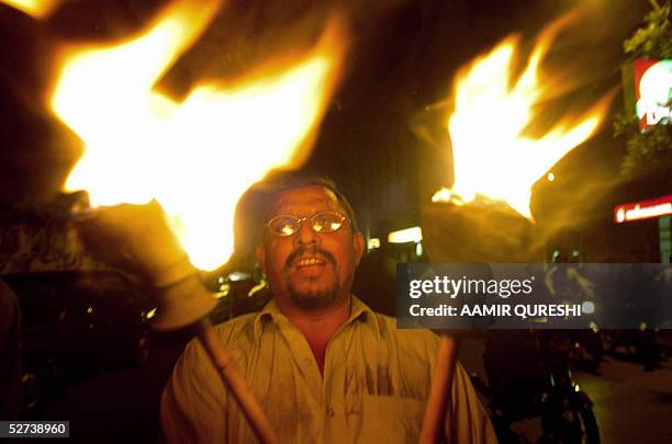 Pakistani Labour Union activist chant slogans as he carries a pair of flaming torches during a rally in Karachi, 30 April 2005, on the eve of...