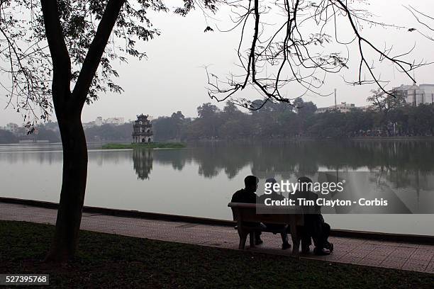 Early morning beside Hoan Kiem Lake, Hanoi, Vietnam, with the Thap Rue Pagoda visible in the distance. Hanoi is the capital of Vietnam and the...