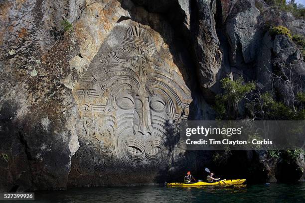 Kayakers visit the Maori rock carvings at Mine Bay, Lake Taupo. The Maori rock carvings are over 10 metres high and are only accessible by boat. The...