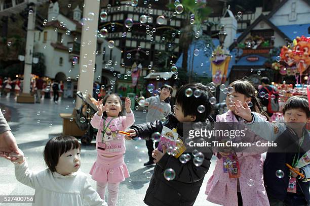 Young Korean children enjoy bubbles sprayed at Lotte World. Lotte World is the world's largest indoor theme park which includes shopping malls, a...