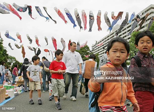 Chrildren walk under fluttering carp streamers at a free market in a park in Tokyo, 01 May 2005, as part of an annual event for Japan's national...