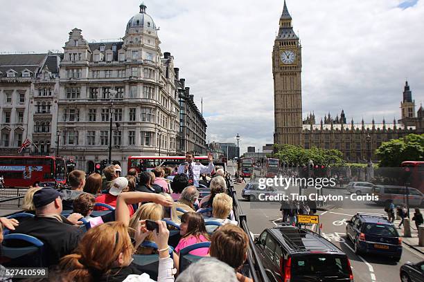 London tour bus full of tourists approaches Big Ben and the Houses of Parliament. Big Ben is to chime non-stop for three minutes to help ring in the...