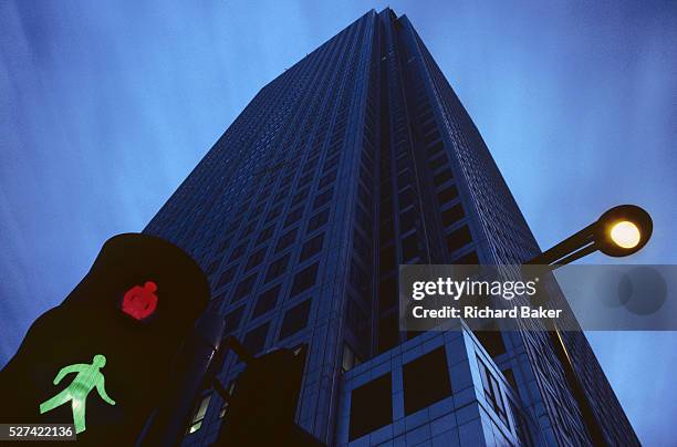 Canary Wharf tower seen from below, London Docklands, East London England. A pedestrian light shows both green for walk and red for don't walk while...