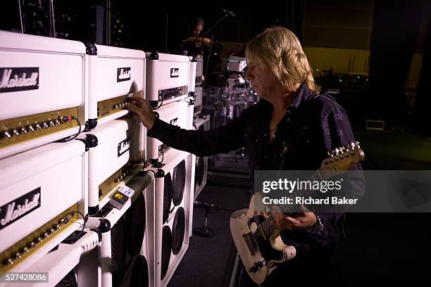 Holding one of his favourite battered guitars is Rick Parfitt, one of the two original members of the rock bank Status Quo and we see him altering...