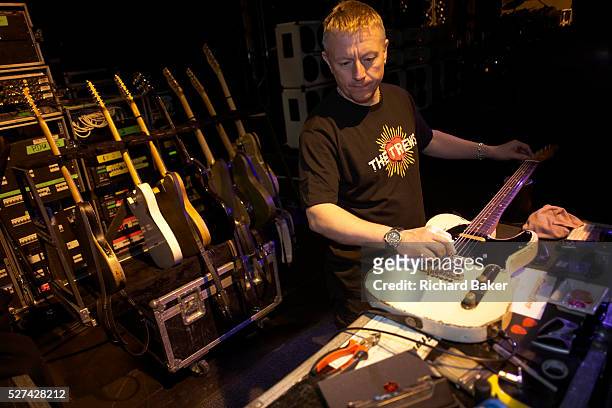 Guitar technician Lloyd Gilbert of the Status Quo rock band tunes one of the band's guitars by stretching the strings to ensure they are tuned...