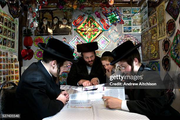 Mr Leibowitz and his 3 sons reading the Torah inside their sukkah during Sukkot, the feast of Tabernacles. The holiday commemorates the forty-year...