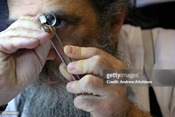 An Orthodox Jewish diamond dealer examines one of his many diamonds at a Hatton garden workshop, London. Hatton Garden is the diamond centre of...