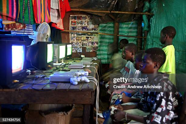 Young Malian teenagers play a football game on Sony Playstation game consoles at a market stall in the local market of Bamako, Mali.