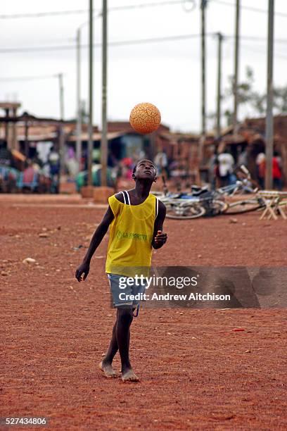 Young boy plays football barefoot on the streets of Ouagadougou, the capital of Burkina Faso. People playing football in any location big enough is a...