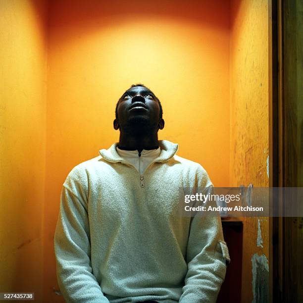 Frank who makes regular long distance call to his family in Ghana in a phone booth of a Long distance call shop, Hackney, London