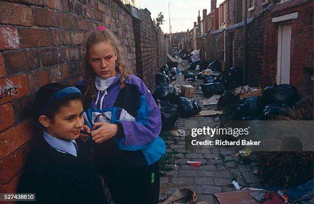 Surrounded by black bin-bags during the Merseyside dustmans' strike of 1991, two young "Scouse' girls lean against a brick wall in a rear alleyway...