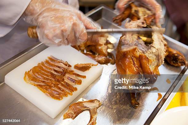 Female chef carves a roast duck in the traditional manner in the main dining room, slicing the breast meat into thin slices, each with a small pieve...