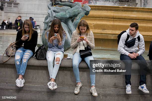 Three teenage girls are lost in the world of smartphone apps and messaging, in Trafalgar Square. While in a very busy environment in the capital's...