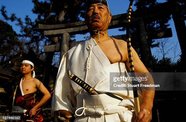 Murata Takeshi and Fujita Takehiro, dressed in traditional Kyudo costumes, stand at the Nashinoki Jinja Shrine. Kyudo is a modern Japanese martial...