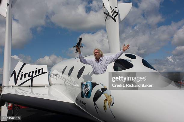 Alongside his SpaceShipTwo vehicle, Richard Branson holds model of satellite LauncherOne after Virgin Galactic space tourism presentation at the 2012...