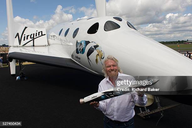 Alongside his SpaceShipTwo vehicle, Richard Branson holds model of satellite LauncherOne after Virgin Galactic space tourism presentation at the 2012...