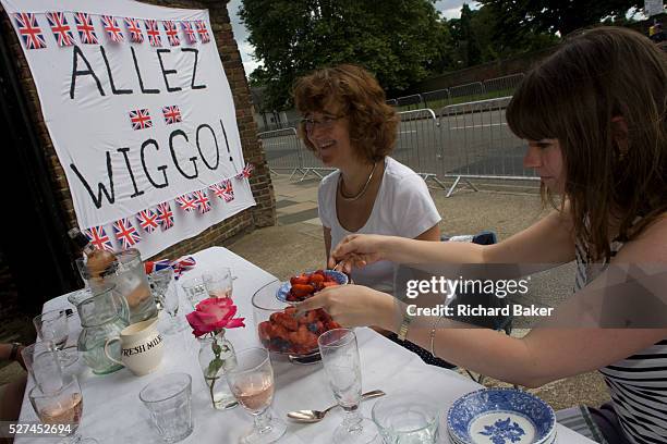 Spectators enjoy a leisurely dessert of strawberries alongside their makeshift banner to Team GB's road cycling hero Bradley Wiggins, a recent winner...