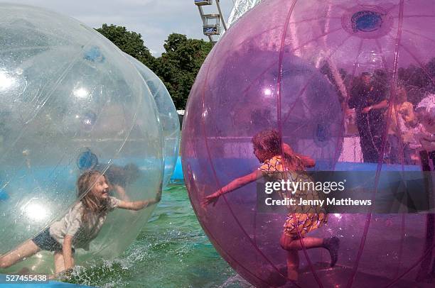 Victoria Park, London Borough of Tower Hamlets. Young girls play inside large plastic balls