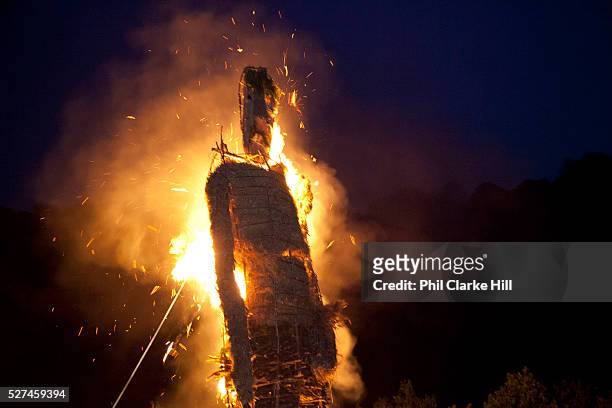 Large straw wickerman burning, on fire as crowd and families watch The annual Beltane celebrations at Butser ancient farm, Hampshire, marking the...
