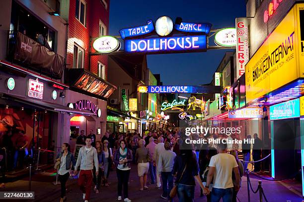 Busy streets with colourful lighting and lots of people very busy, near Beatlesplatz, Reeperbahn and St Pauli, Hamburg, Germany.