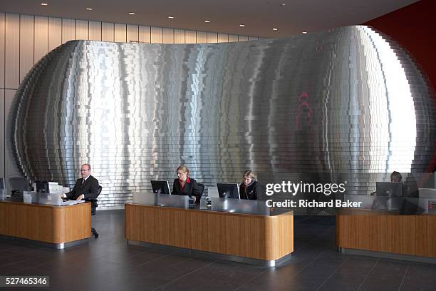 Greeting visitors to Ernst & Young's Norman Foster-designed 385,000 square foot European headquarter are a team of receptionists seated working at PC...