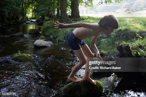 Wearing his bathing costume, a young adventurer clambers over rocks in the Gross Enz river in Germany's Black Forest. The lad of 10 crouches to...