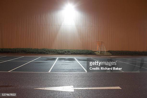 In front of empty parking bay markings, a stencilled arrow points from right to left in the foreground at the DIRFT warehouse logistics park in...