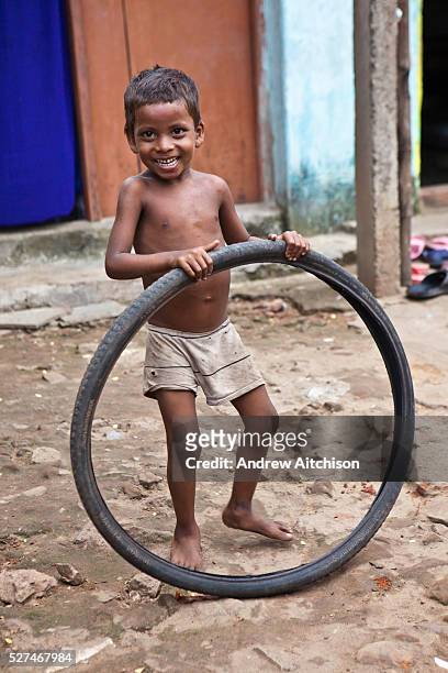 Young boy from the Pilgrim Roam slum plays with an old bicyle tyre. Orissa District, India.