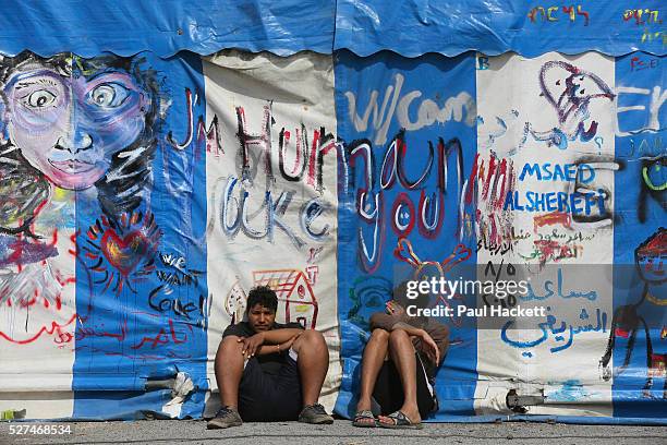 Men sit at 'the Jungle' migrant camp in Calais, France, August 10, 2015. The Calais jungle is the nickname given to a series of camps in the vicinity...