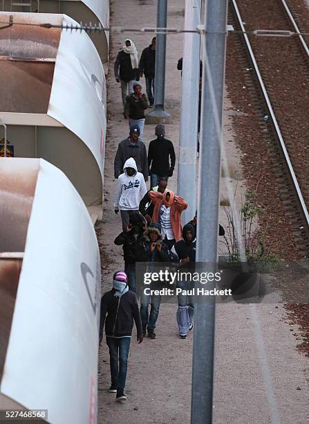 Migrants walk along the railway track leading to the EuroTunnel at night, in Calais, France, August 10, 2015. Migrants are attempting to enter the...