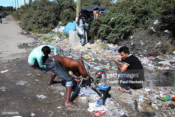 Men wash and shave at 'the Jungle' migrant camp in Calais, France, August 10, 2015. The Calais jungle is the nickname given to a series of camps in...