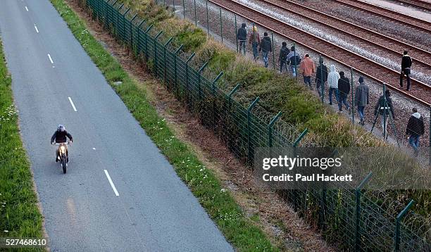 Migrants walk along the railway track leading to the EuroTunnel at night, in Calais, France, August 10, 2015. Migrants are attempting to enter the...