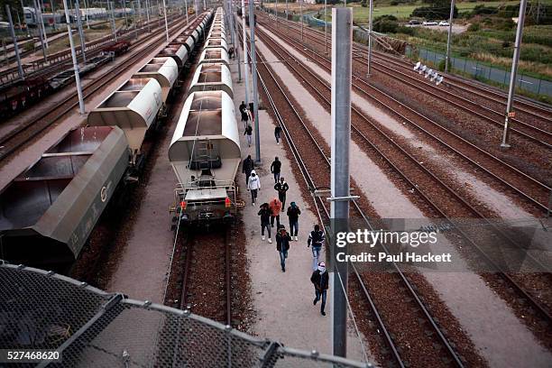 Migrants walk along the railway track leading to the EuroTunnel at night, in Calais, France, August 10, 2015. Migrants are attempting to enter the...